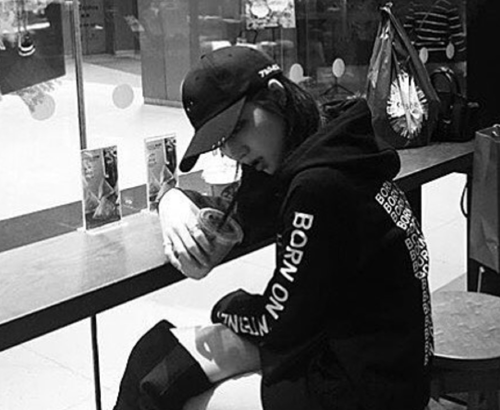 Figure at a mall food-court counter in a dark Born On Internet hooded top.