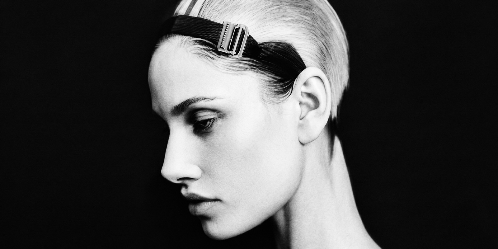 NIIA — wide B&W profile, slicked hair under a hardware headband.
