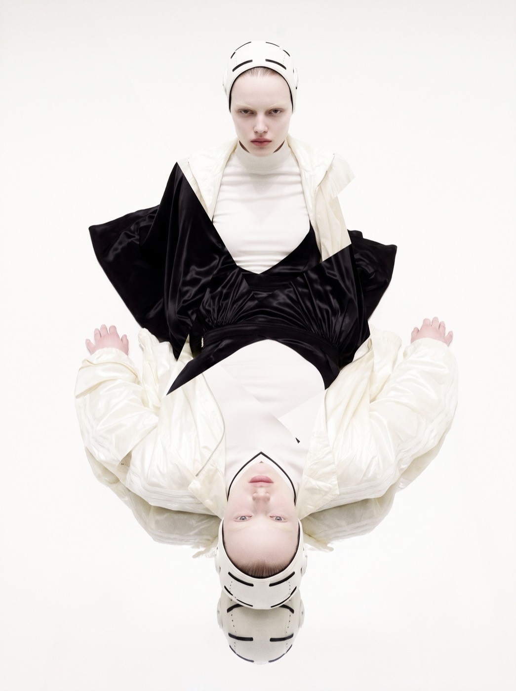 Creative Direction — a figure in a white padded helmet and cream nylon shell over black satin, mirrored on the horizontal into one symmetrical form