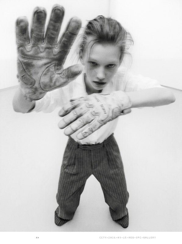 Security still: intern in white shirt and pinstripe trousers holds both dirty gloves toward the camera.